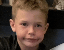 a close up of a young boy 's face with a black shirt on .