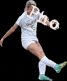 a female soccer player wearing a number 5 jersey is kicking a soccer ball .