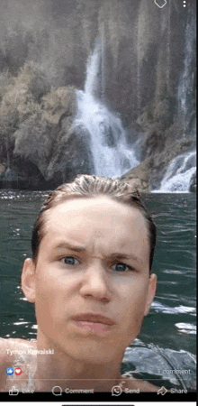 a picture of a young man in the water with a waterfall in the background