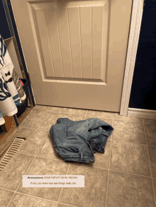 a pair of jeans laying on a tiled floor next to a door