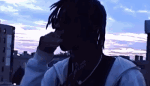 a silhouette of a man with dreadlocks covering his nose with his hand