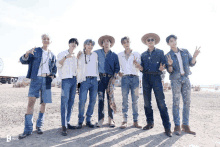 a group of men in cowboy hats and jeans pose for a photo in the desert