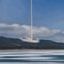 a rocket is being launched into the sky above a body of water