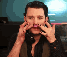 a man with black nail polish on his fingers holds a pink object to his mouth