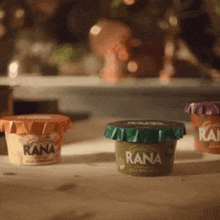 three cups of rana yogurt are on a table