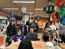 a group of people are sitting around a pizza box that says pizza on it