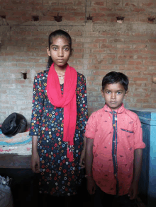 a girl wearing a red scarf stands next to a boy wearing a red shirt that says ' tommy hilfiger '