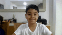 a young boy in a white shirt is smiling in front of a canon printer