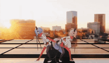 two anime characters are dancing in front of a city skyline at sunset