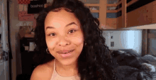 a woman with braces on her teeth is smiling in front of a bunk bed in a dorm room .