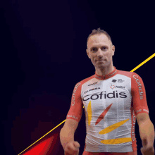 a man wearing a red and white cofidis jersey gives a thumbs up