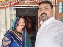 a man and a woman are posing for a picture in front of a sign that says ' shree ' on it