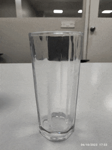 a clear glass sitting on a table with the date 06/10/2023