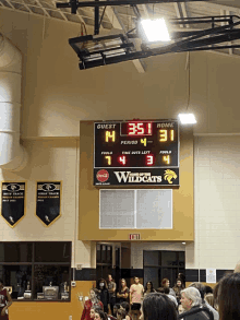 a scoreboard in a gym shows that the wildcats are leading the guests