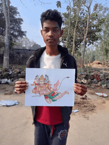 a young man holding a drawing of hanuman