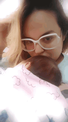 a woman wearing glasses is holding a baby