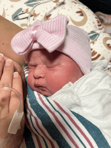 a newborn baby wearing a pink hat with a pink bow