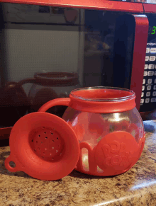 a red pop corn maker sits on a counter next to a microwave