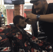 a man is getting his hair cut by a man wearing a shirt that says ' n ' on it