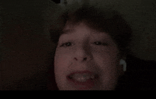 a young boy with braces on his teeth looks at the camera in the dark