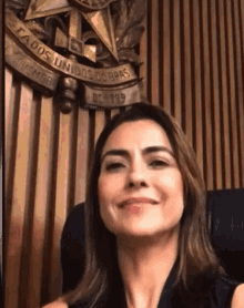 a woman is smiling in front of a wooden wall with the words estados unidos do brasil written on it