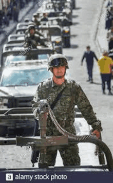 a soldier is holding a machine gun in front of a row of military vehicles .