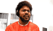 a man with a beard wearing headphones and a red tie dye shirt