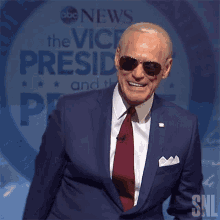 a man in a suit and tie is smiling in front of a sign that says abc news the vice president and the president