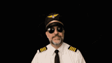 a man wearing a pilot 's hat and sunglasses holds his fist up in the air