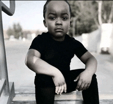 a black and white photo of a young boy sitting on steps