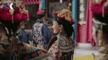 a woman in a very elaborate costume is sitting in front of a sign that says ' tc ' on it