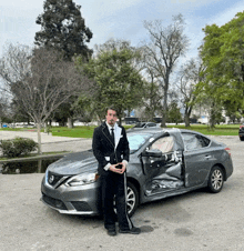 a man in a tuxedo stands in front of a nissan