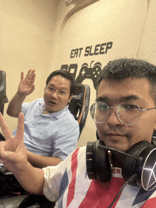 two men are sitting in front of a sign that says eat sleep