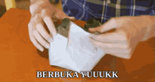 a person is holding a piece of paper that says " berbuka yuuukk " on it