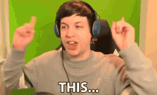 a man wearing headphones and a grey sweater says " this "