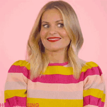 a woman wearing a colorful striped sweater is smiling and looking at the camera .