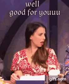 a woman in a red and white dress is sitting at a table with a box of tissues in front of her .