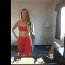 a woman is taking a selfie in front of a mirror in a room .