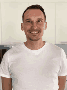 a man wearing a white t-shirt is smiling for the camera