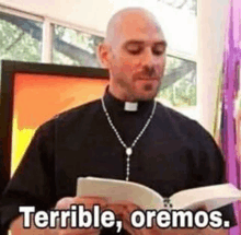 a priest is reading a book with the words `` terrible , oremos '' written on it .