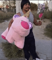 a man holding a pink stuffed unicorn and a balloon