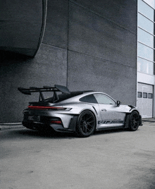 a porsche 911 gt3r is parked in front of a gray building