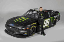 a man stands in front of a monster energy sponsored race car