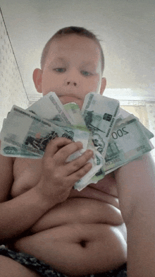 a boy is holding a stack of russian money