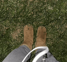 a person wearing a pair of brown boots is standing in a field of grass