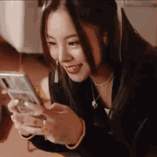 a young woman is sitting on the floor looking at her cell phone .