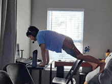 a man is doing push ups on a folding chair in front of a desk .