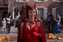 a woman in a red cape and gloves smiles