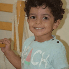 a young boy wearing a shirt that says beach smiles for the camera