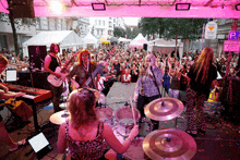 a group of people playing instruments on a stage with a sign in the background that says parking only